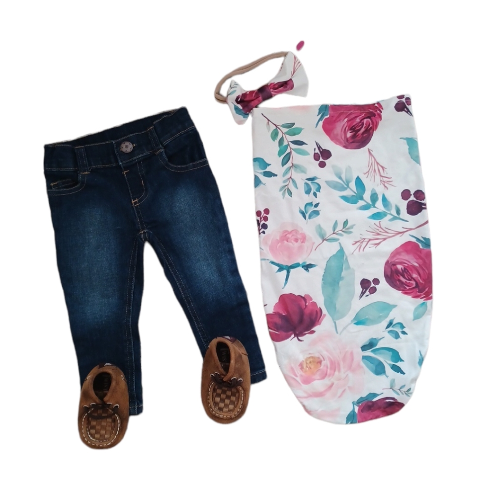 A newborn snuggle sack with matching bow and jeans and little shoes